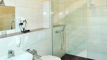 Un baño moderno con ducha de vidrio, lavamanos blanco y un inodoro.