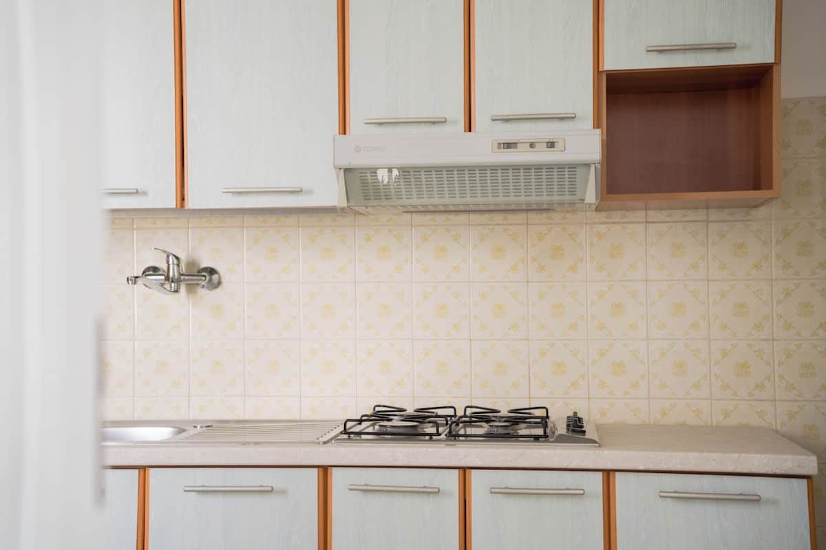 Una cocina con armarios de color claro, una estufa a gas y una campana extractora de pared.
