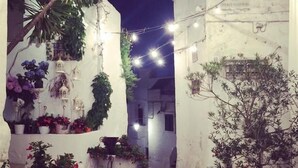 A narrow alleyway with string lights, potted plants, and a tiled floor. - Blumarine Residence Club (Ostuni)