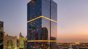 A high-rise building with the name 'WYNDHAM' at the top, surrounded by other buildings and a cityscape at dusk. - Wyndham Doha West Bay (Doha)