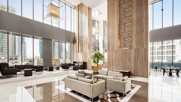 A spacious lobby with modern furniture, large windows, and a view of the cityscape. - Wyndham Doha West Bay (Doha)