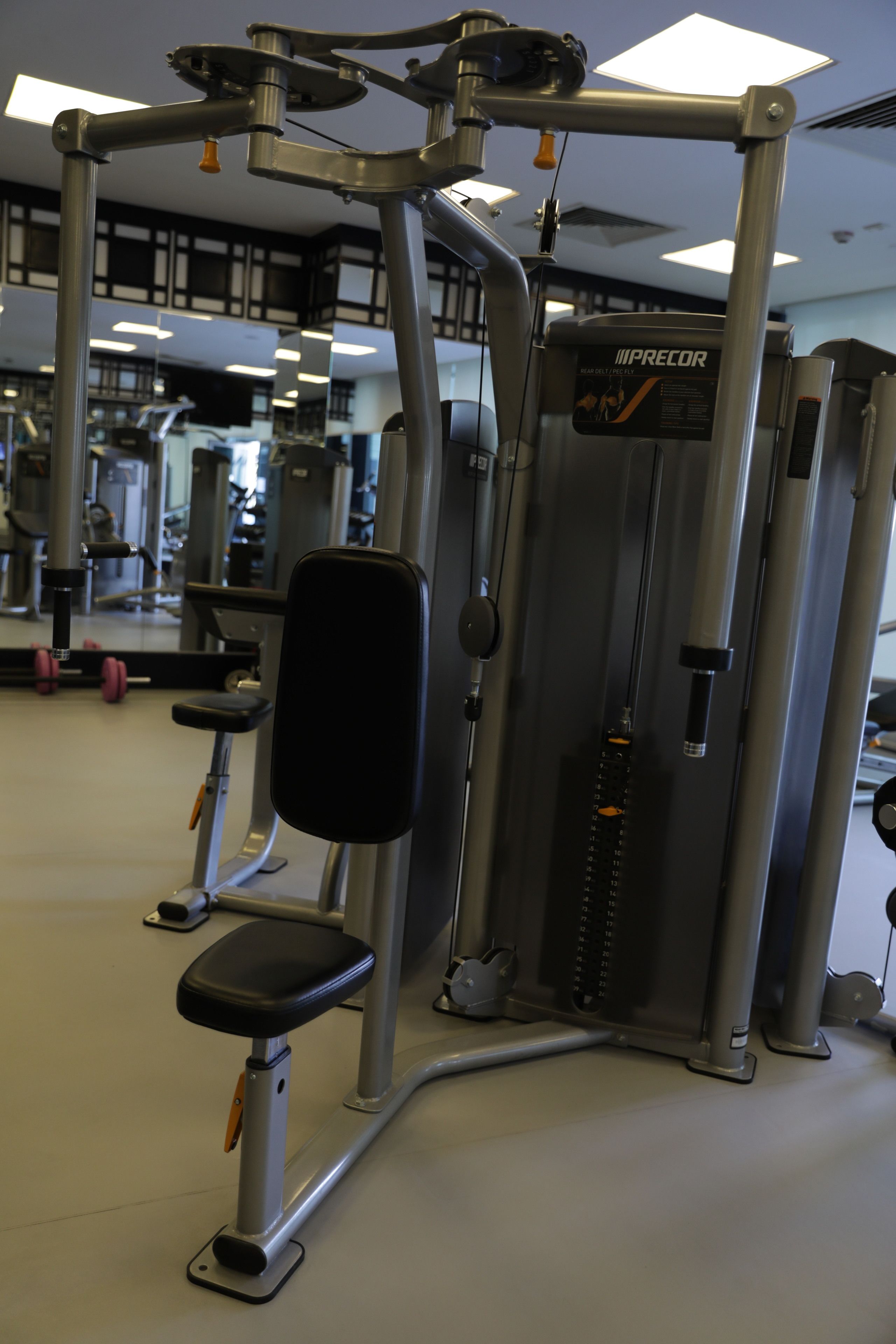 Uma academia com diversos equipamentos de exercício, incluindo um puxador dorsal e uma prensa de pernas.