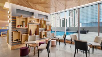 A modern lounge area with wooden shelving, comfortable seating, and a view of the city skyline.