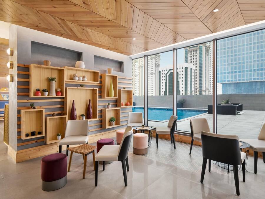 A modern lounge area with wooden shelving, comfortable seating, and a view of the city skyline.