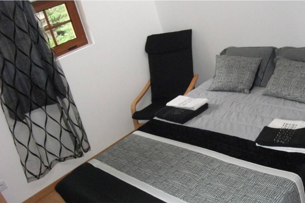 A bedroom with a bed, a chair, and a window.