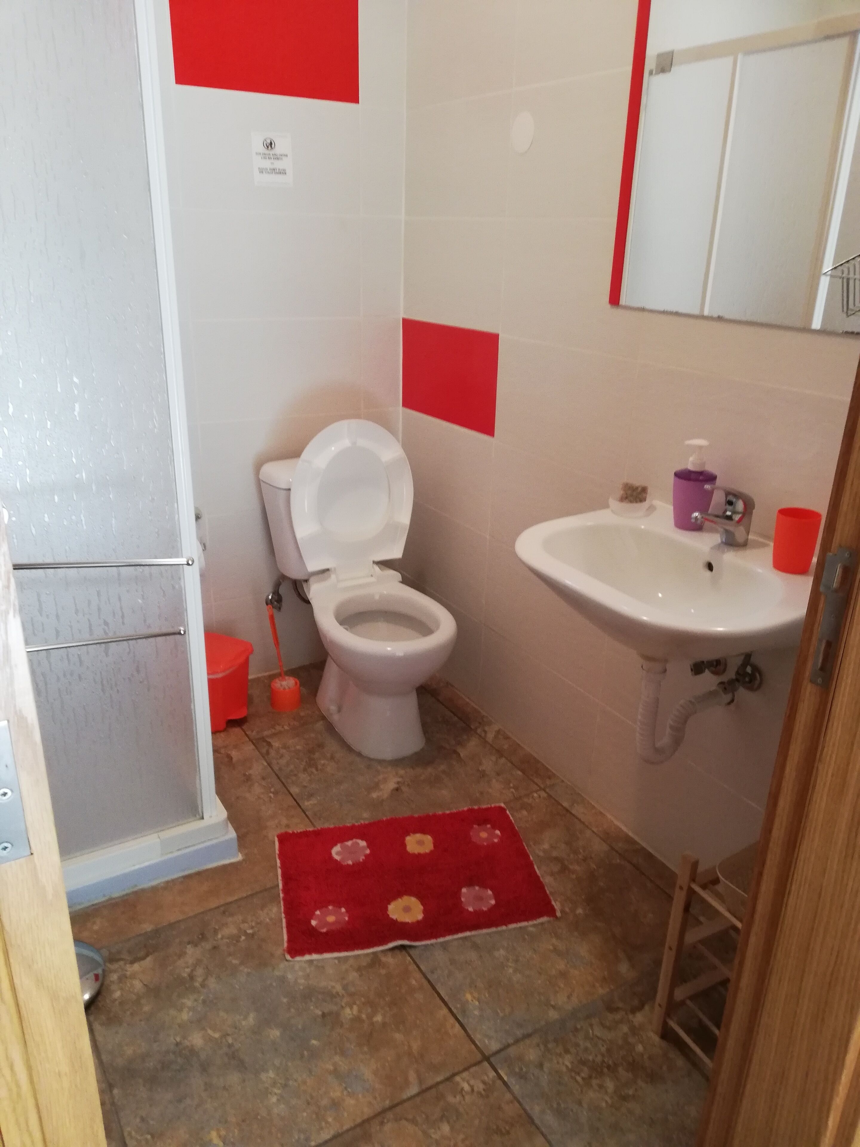 A small bathroom with a toilet, sink, and shower.