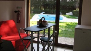 Una habitación con un sofá rojo, una mesita con una cesta de frutas y vistas a una piscina exterior.