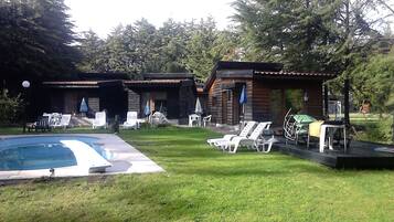 A pool area with lounge chairs and a wooden cabin structure.