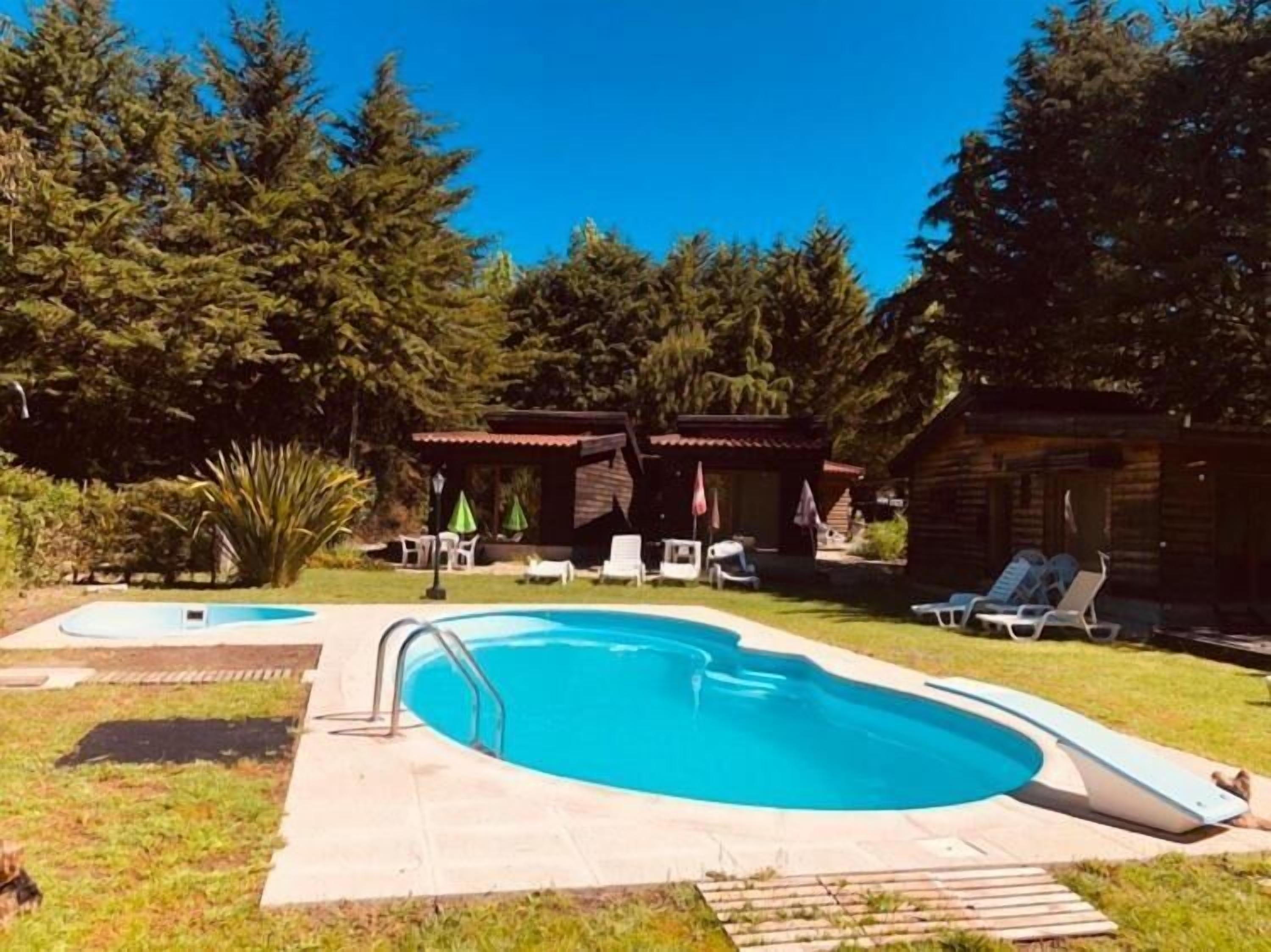 Una piscina al aire libre, sombrillas, tumbonas