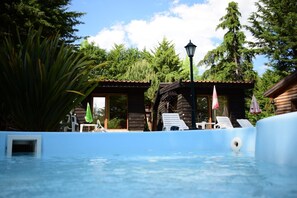 A pool area with wooden cabins, lounge chairs, and a lamppost. - Quinta Sul America (Moimenta da Beira)