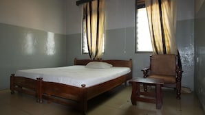Un dormitorio con una cama y una silla de madera, además de una mesita.