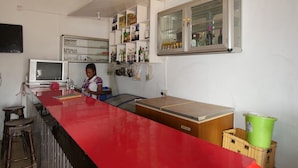 Una cocina con encimera roja, una ventana y estantes con botellas.