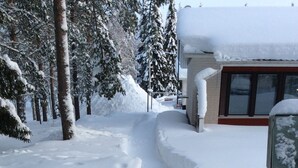 Un sendero cubierto de nieve que conduce a un edificio con fachada de ladrillo y grandes ventanales.