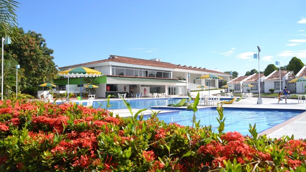 A hotel with a swimming pool, outdoor seating, and a green umbrella. - Hotel Albatros (Espinal)