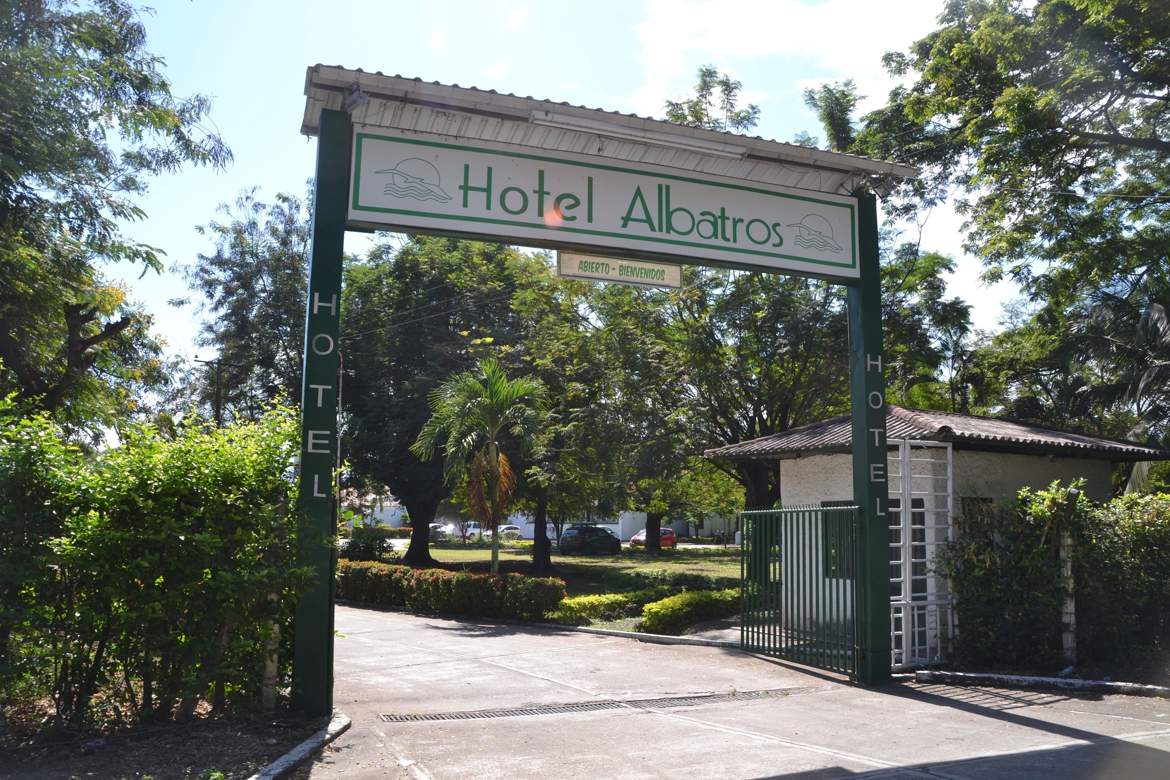 Entrada de un hotel con un letrero que dice "Hotel Albatros" y un cartel de bienvenida.