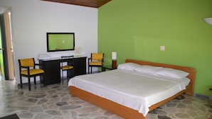 A bedroom with a bed, a desk, two chairs, a mirror, and a nightstand. - Hotel Albatros (Espinal)