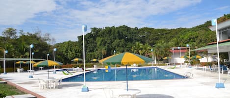 Una piscina al aire libre, sillones reclinables de piscina