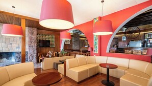Un área de estar moderna con sofás de cuero, mesas de madera e iluminación colgante roja.