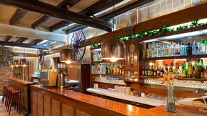 Zona de bar con mostradores de madera, luces colgantes y una variedad de botellas de licor.