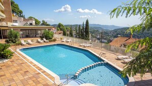 Una piscina con tumbonas y vistas del paisaje circundante.