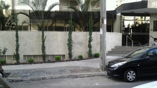 A building entrance with a black car parked in front. - Apartamento 3 quartos Bueno (Goiania)