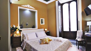A bedroom with a large bed, a mirror, a nightstand with a lamp, and a window with curtains. - Art Fashion House Luxury Rooms (Catania)