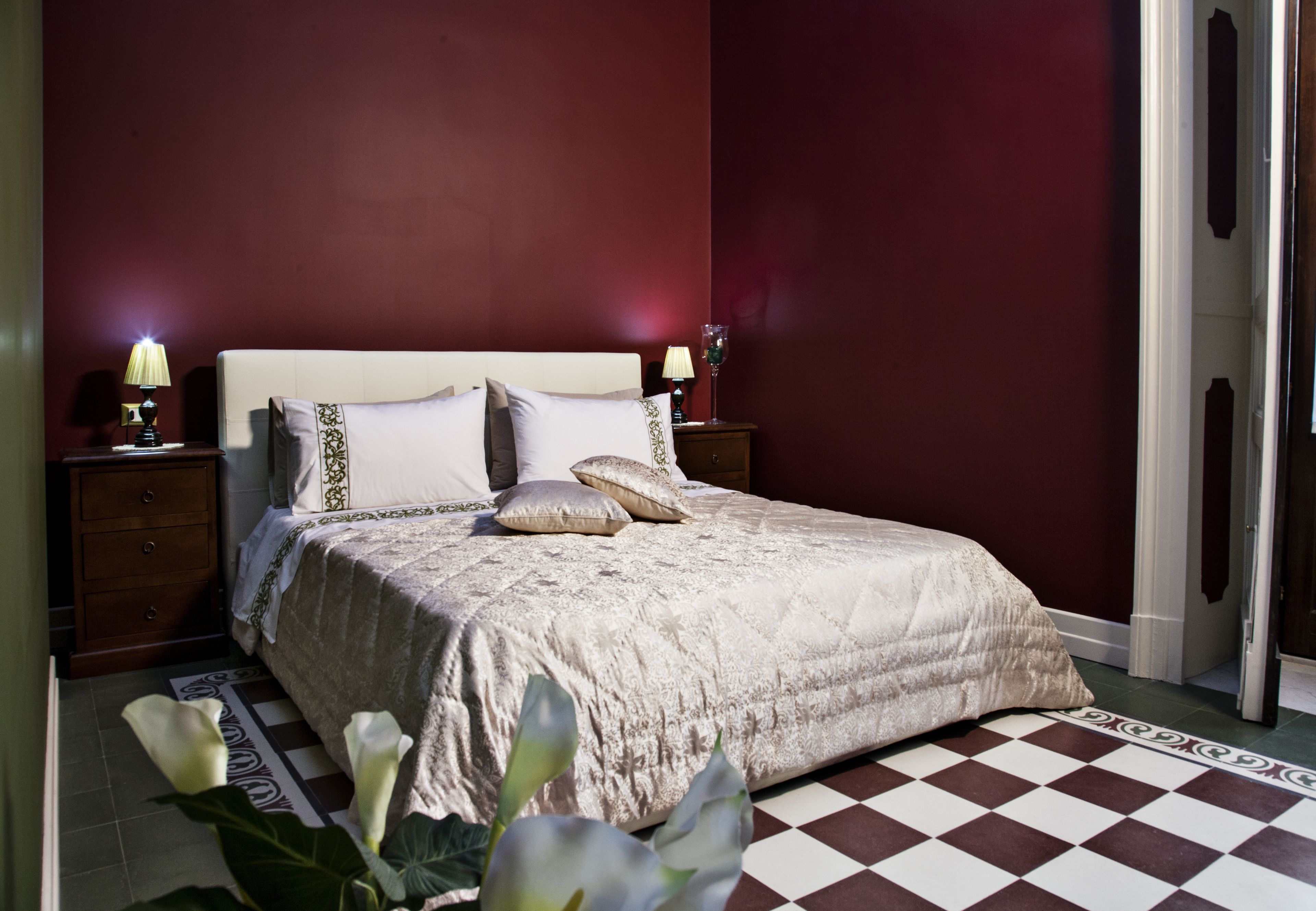 A neatly made bed with a patterned bedspread, two bedside lamps, and a nightstand with a lamp.