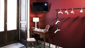 A room with a wooden desk, a chair, a television mounted on the wall, and a mirror on the wall. - Art Fashion House Luxury Rooms (Catania)