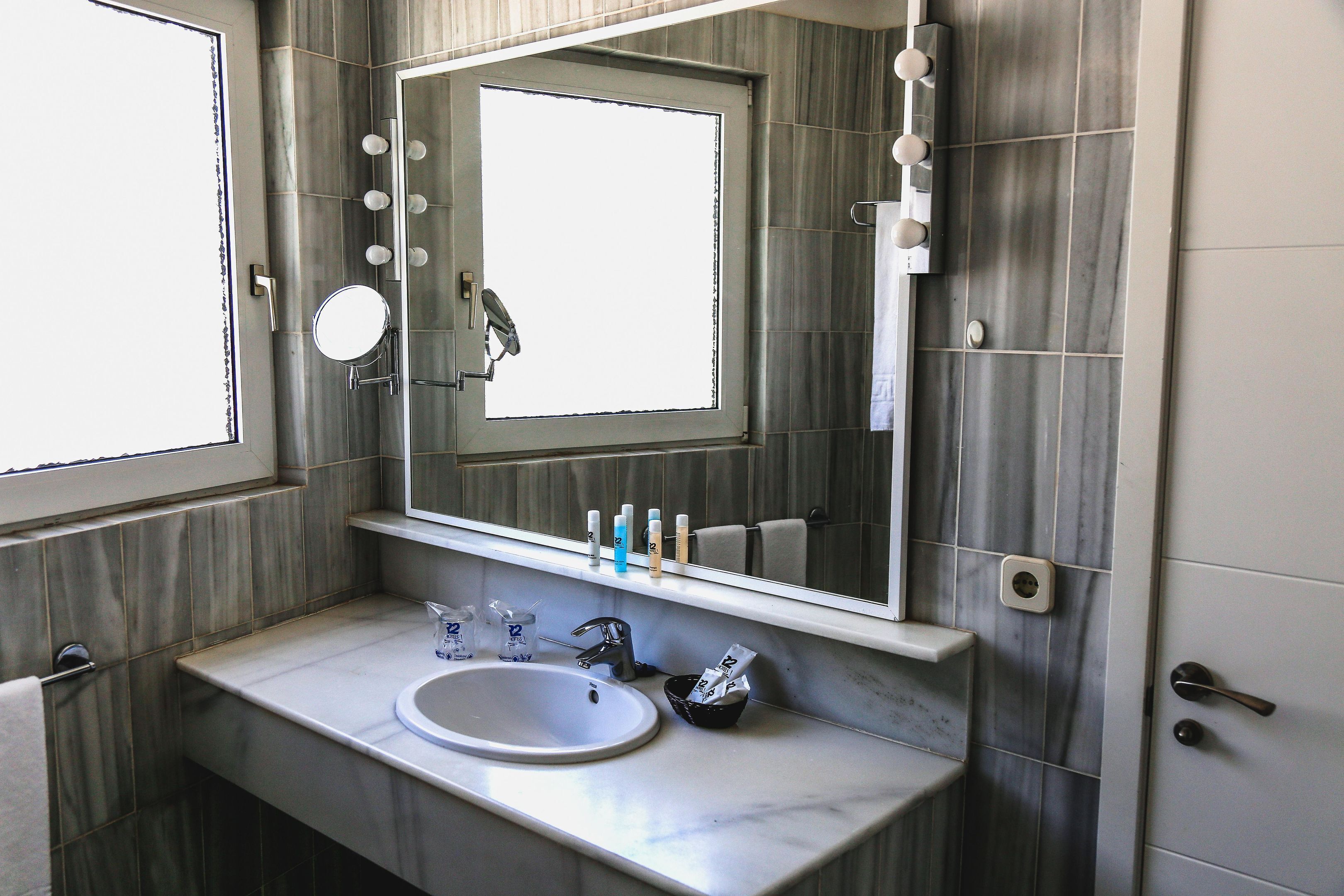 A bathroom with a sink, mirror, and toiletries.