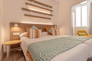 A modern hotel room with a large bed, a bedside table, a chair, and a window with curtains. - R2 Maryvent Beach Apartaments (Pajara)