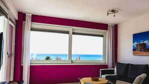 Una habitación con un ventanal grande que ofrece vista al mar, una mesa con un cuenco, un sofá y una lámpara en el techo.