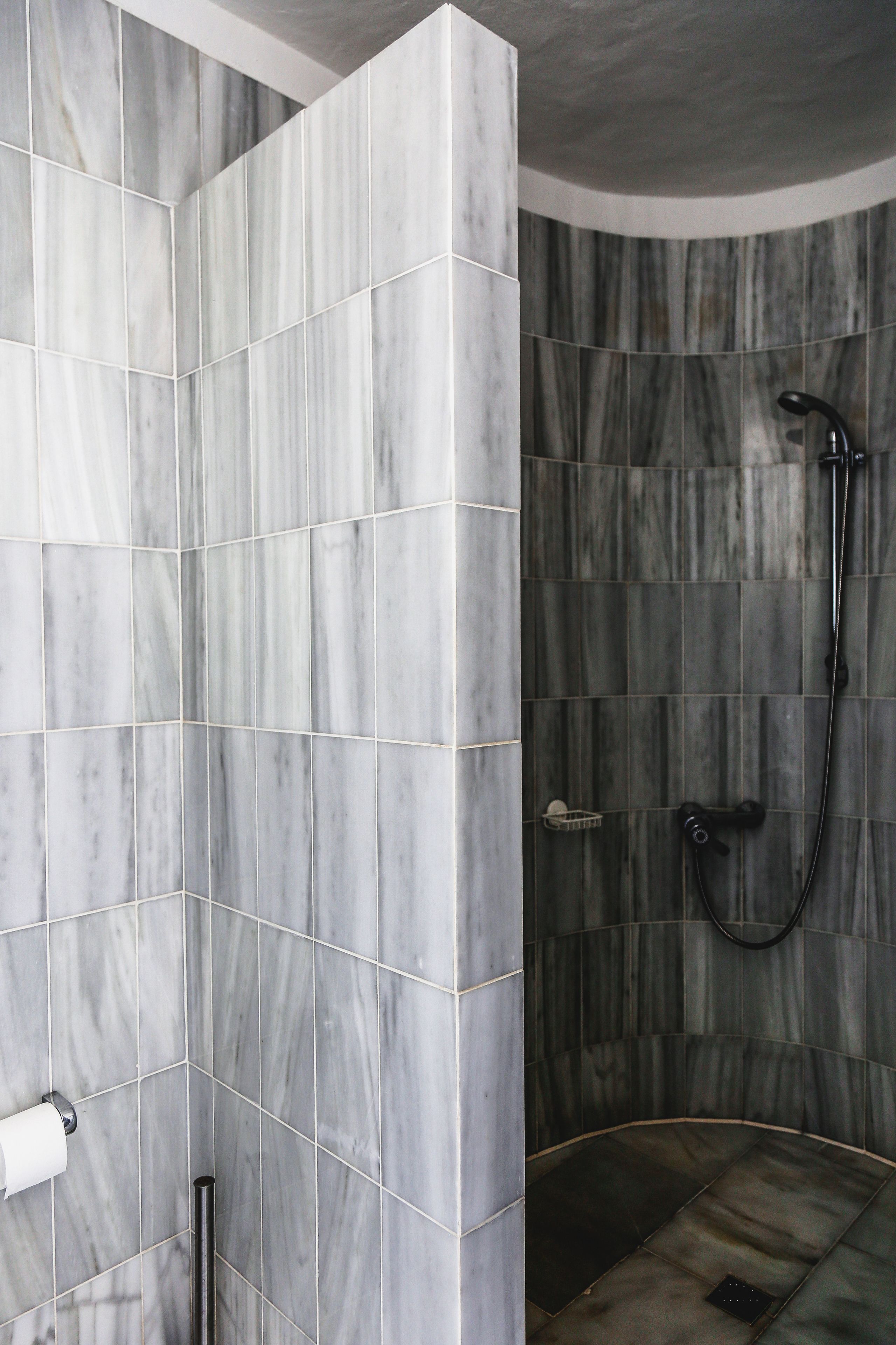 A bathroom with marble tiles, a shower area, and a toilet.