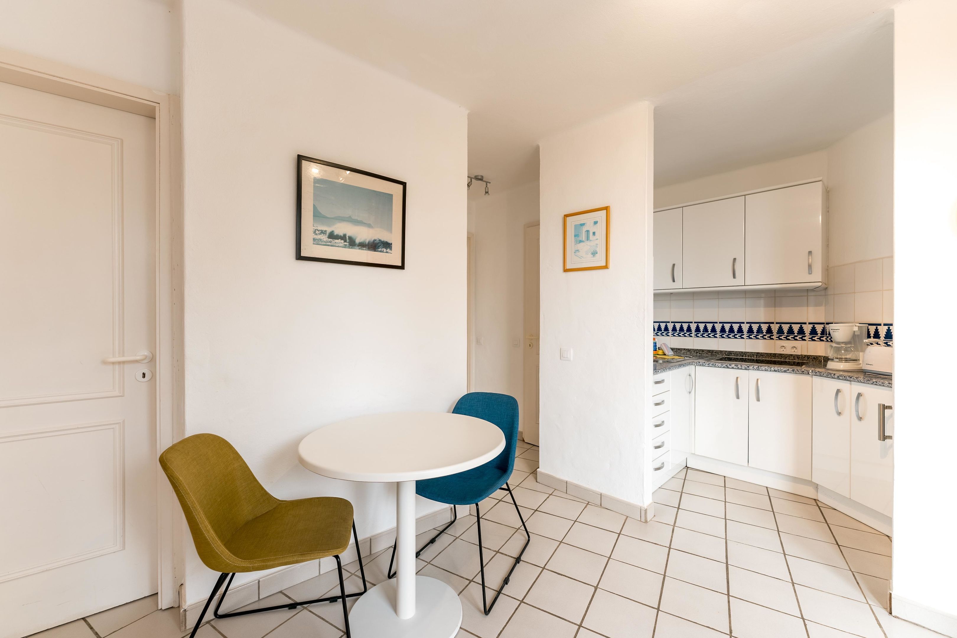 A small, clean kitchen with white cabinets and a tiled floor.