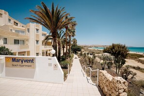 A Maryvent Beach Apartment with a stone pathway leading to the beach, palm trees, and a clear view of the ocean. - R2 Maryvent Beach Apartaments (Pajara)