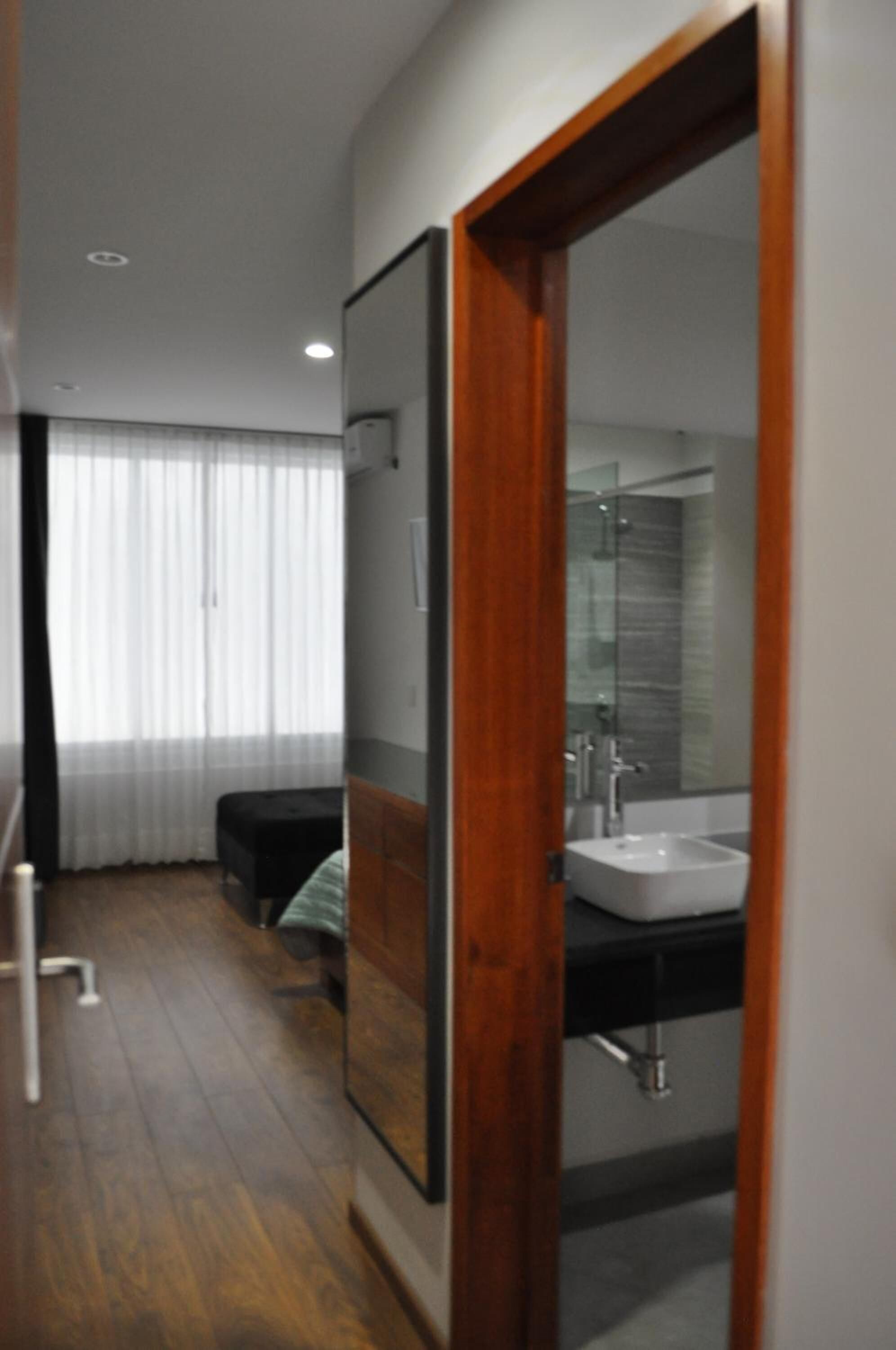 A modern bathroom with a large mirror, a sink, and a shower area.