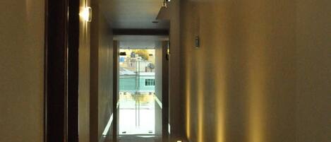 A hallway with a view of a pool and a building in the distance.