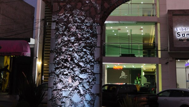 Un edificio moderno con un llamativo letrero de AMD, un arco de piedra y un frente de vidrio.