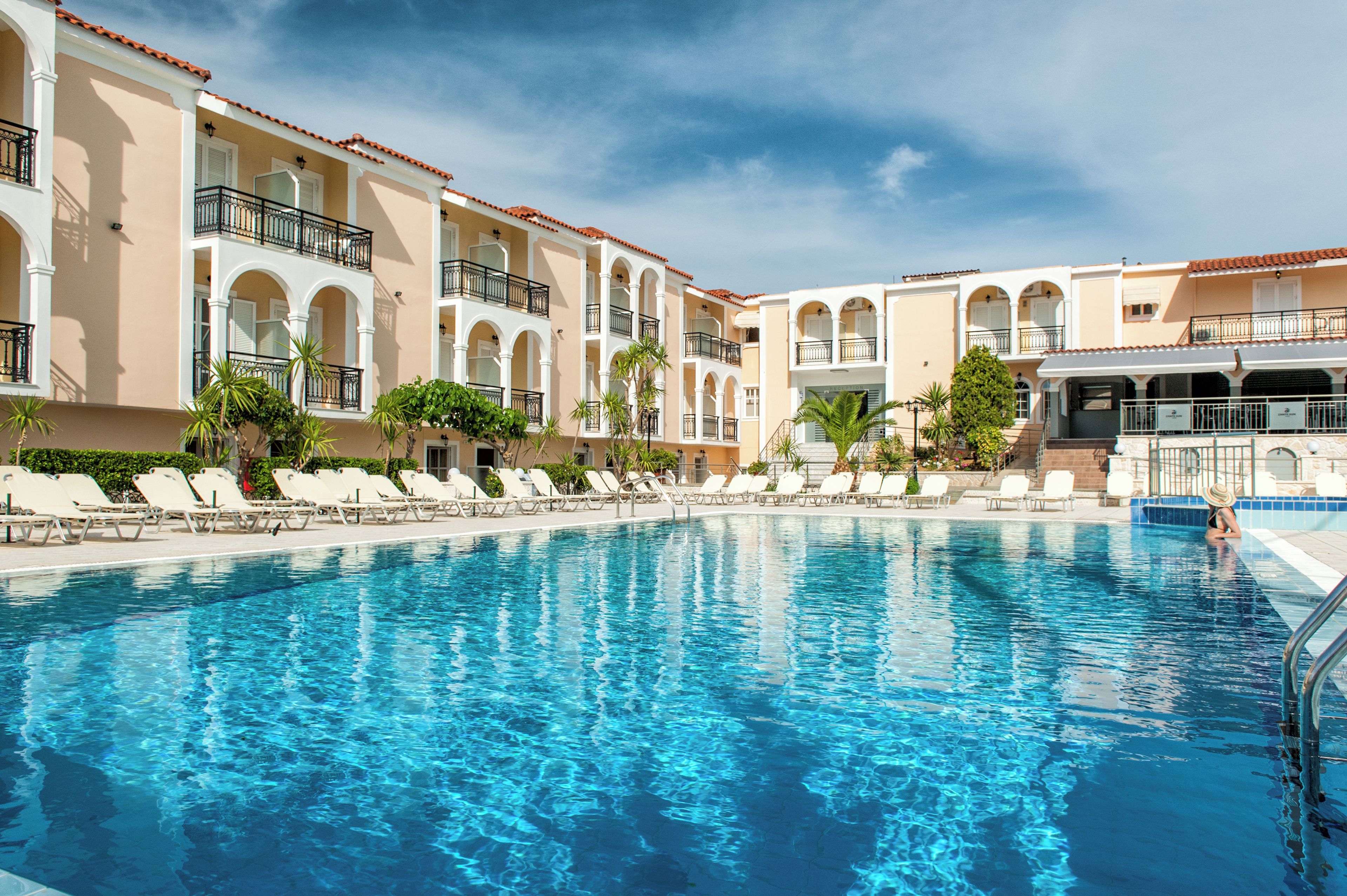 A swimming pool with lounge chairs and a building with balconies.