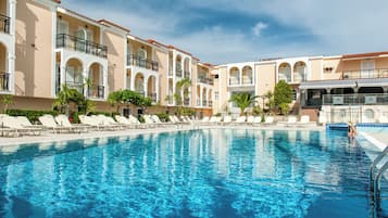 A swimming pool with lounge chairs and a building with balconies.