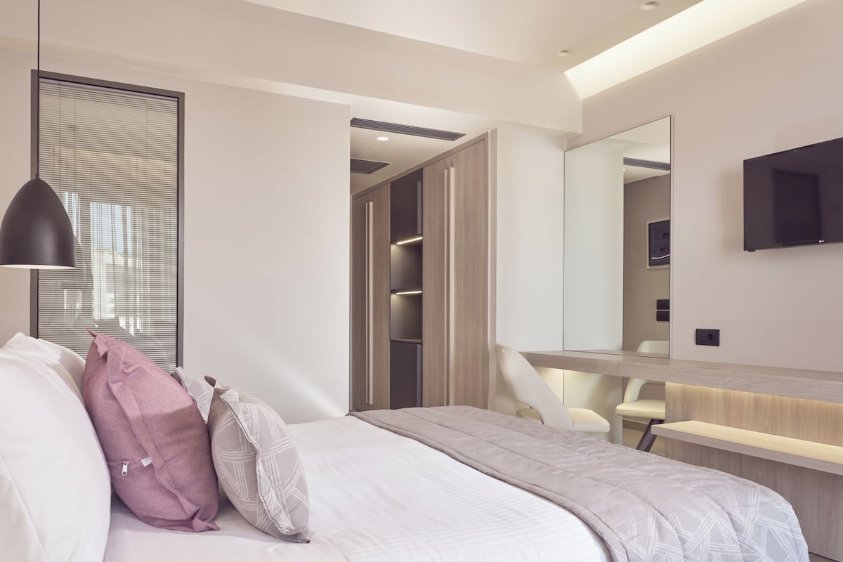 A modern bedroom with a bed, bedside table, and a large mirror.
