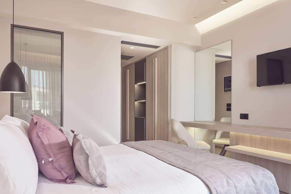 Um quarto moderno com cama, mesa de cabeceira e um espelho grande.