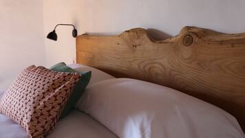 Una cama con cabecera de madera, un cojín estampado y un cojín verde.