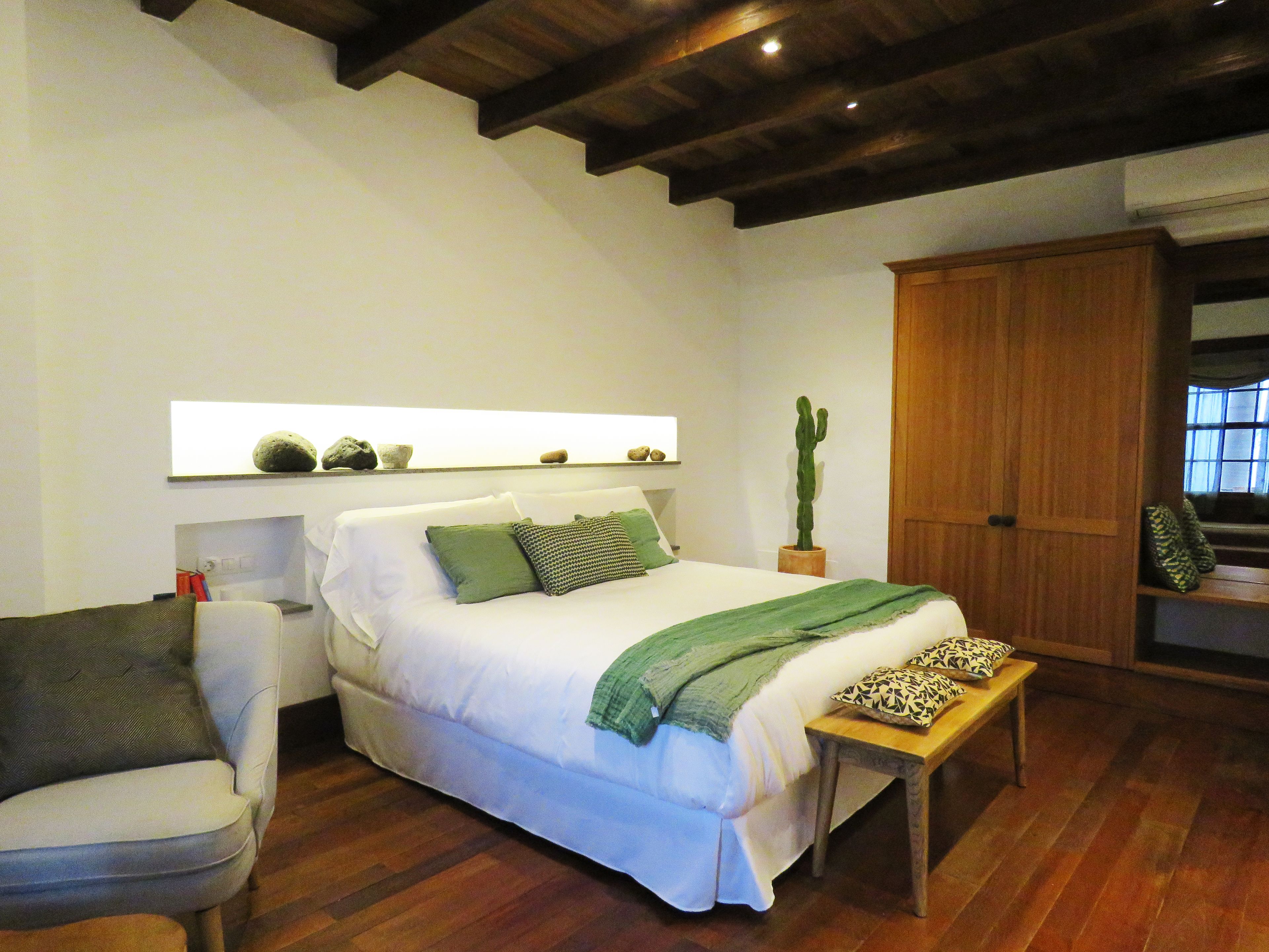 Ein Schlafzimmer mit einem Bett, einer Holzbank, einem Kaktus und einem Kleiderschrank.