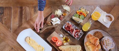 Una mesa de desayuno con diversos alimentos, incluyendo queso, frutas, pan y pasteles.