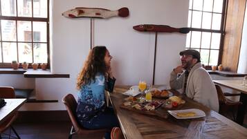 Un espace repas avec des tables et des chaises en bois, une variété de plats disposés sur les tables et des poissons décoratifs accrochés au mur.