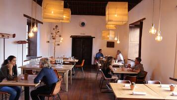 Un restaurante con mesas y sillas de madera, lámparas colgantes y una decoración rústica.