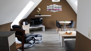Un appartement moderne de style « loft » comprenant un coin repas, un espace salon et un téléviseur.