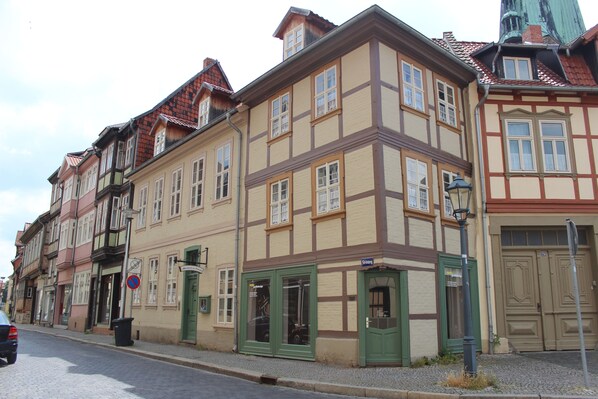 A row of traditional European buildings with multiple stories, featuring timber framing and a variety of window styles. - Appartments am Brunnen (Quedlinburg)