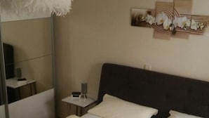Une chambre d’hôtel avec un grand lit, une table de chevet avec une lampe, un miroir et une œuvre d’art murale.