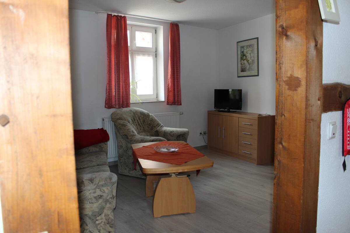 Een woonkamer met een bank, een houten tafel, een televisie en een kast.
